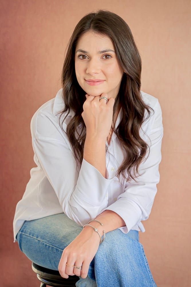 Dra. Carla Eid Gobbi sorrindo, sentada, de camisa branca